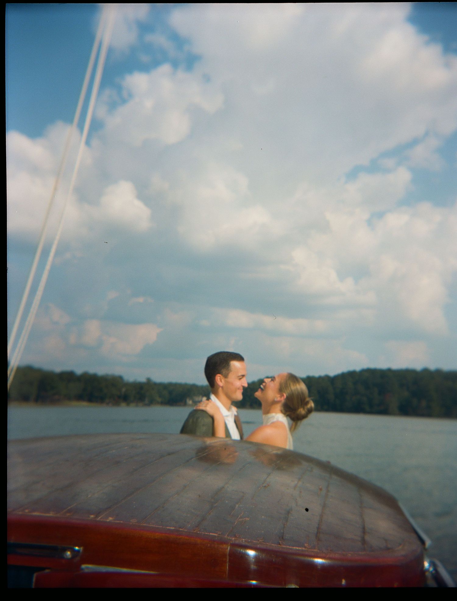 Couple enjoying a romantic moment on a boat with water and cloudy sky in the background.