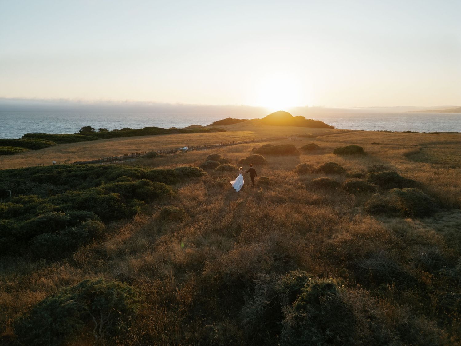 Golden sunset over coastal hills with silhouettes against the horizon.
