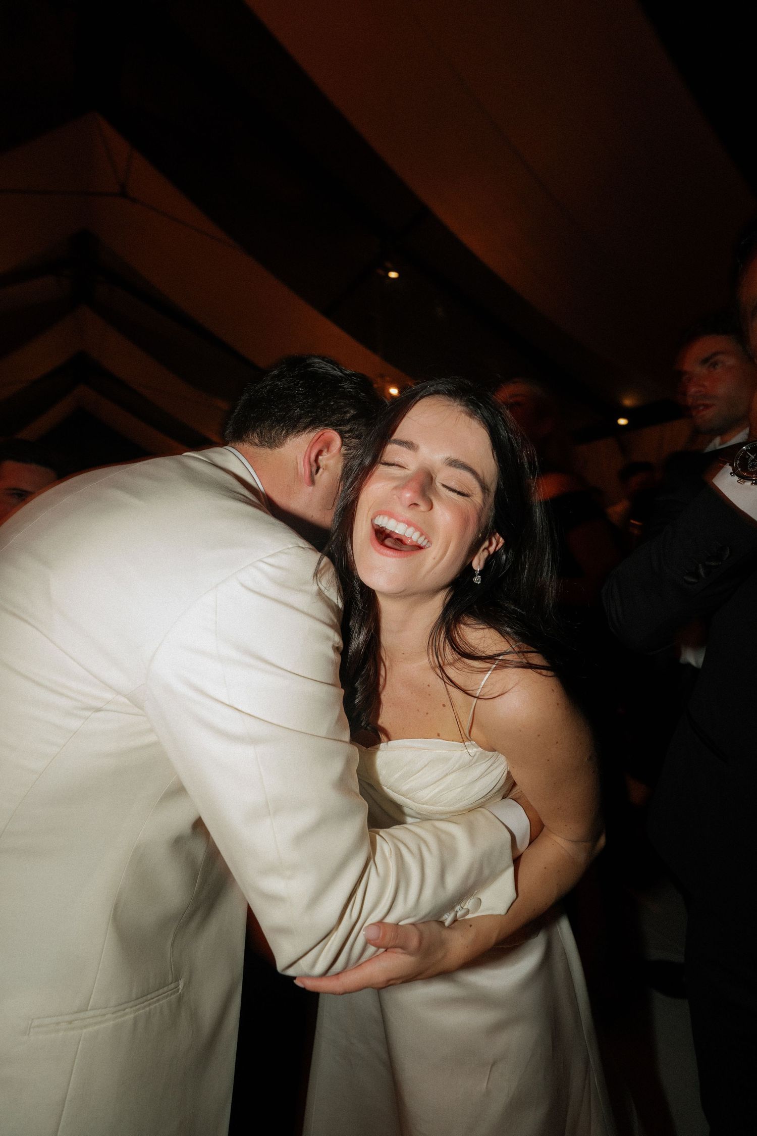 A joyful moment captured during a wedding reception dance in dramatic lighting.
