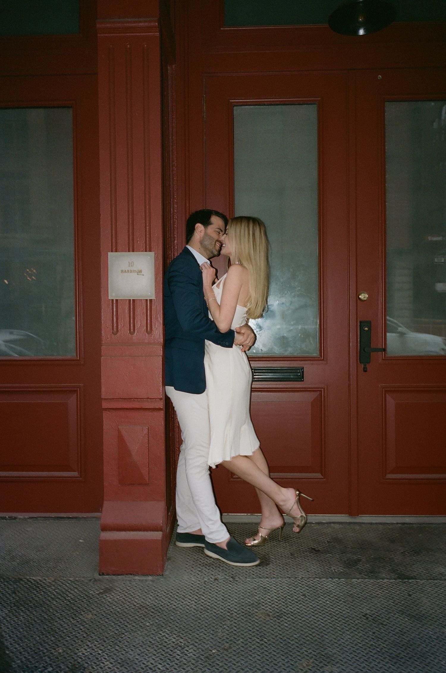 A romantic moment between a couple against red doors of a building.
