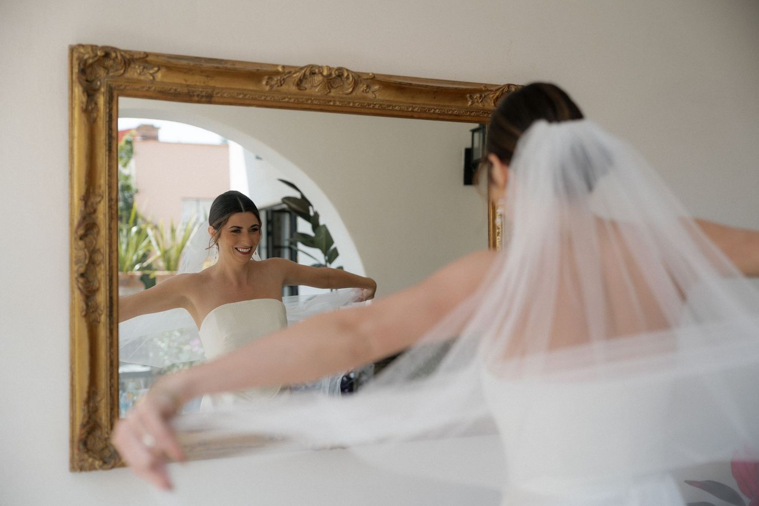 Artistic sequence showing flowing white wedding veil movement in a framed mirror.