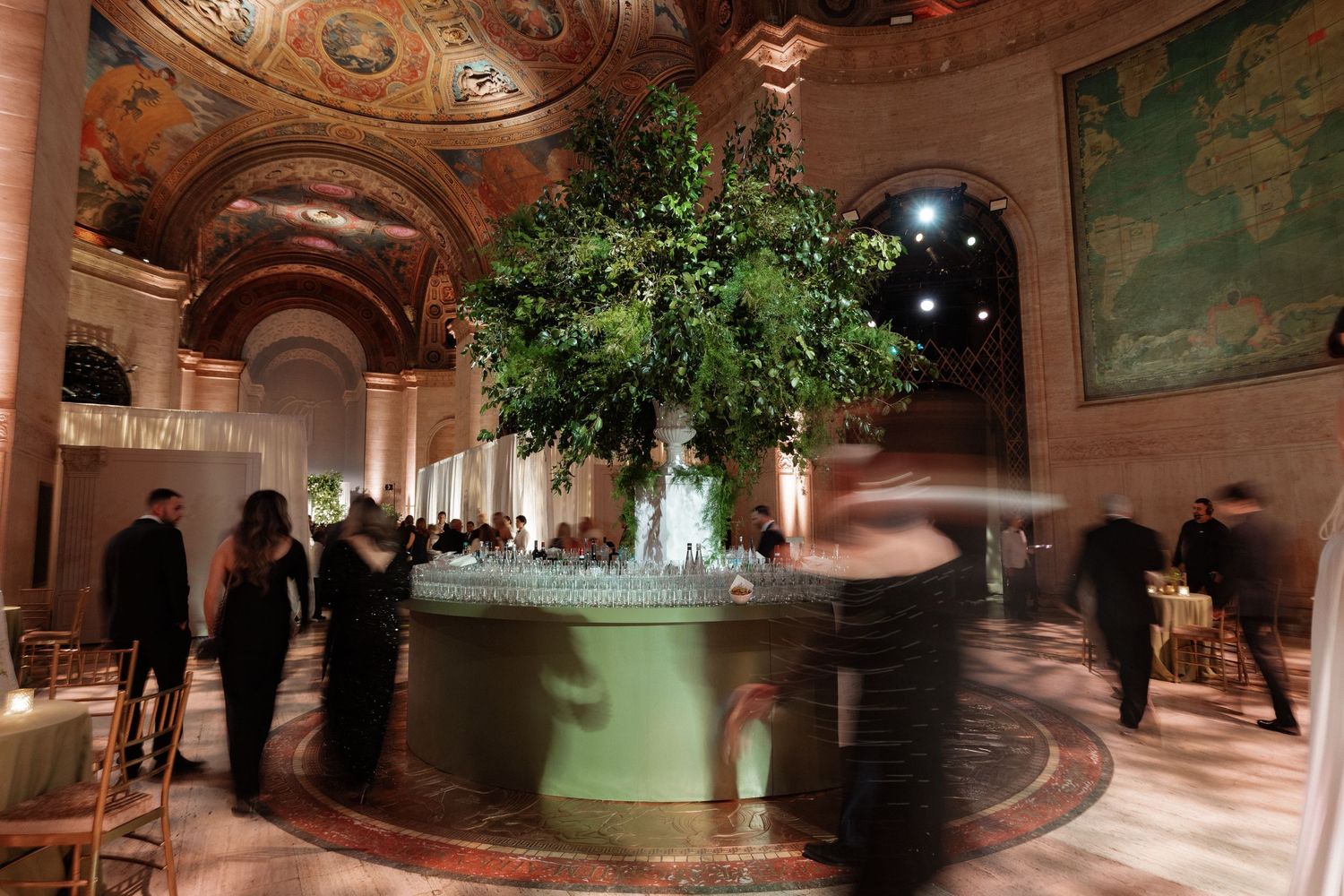 A large, ornate interior with a grand floral centerpiece and people walking through the space.