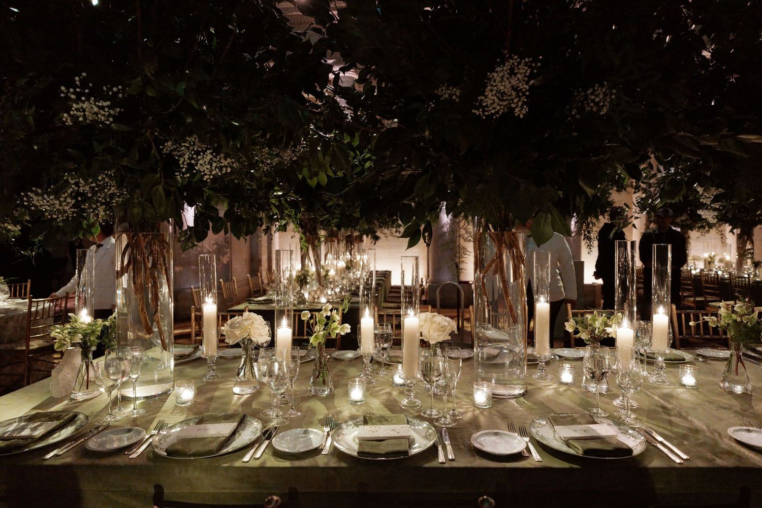 A beautifully decorated wedding reception table with glassware, candles, and a lush floral centerpiece.