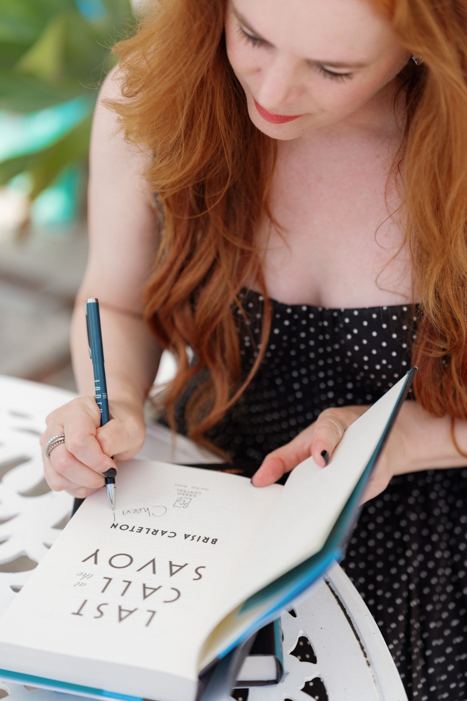 A young woman with long red hair writing in a notebook.
