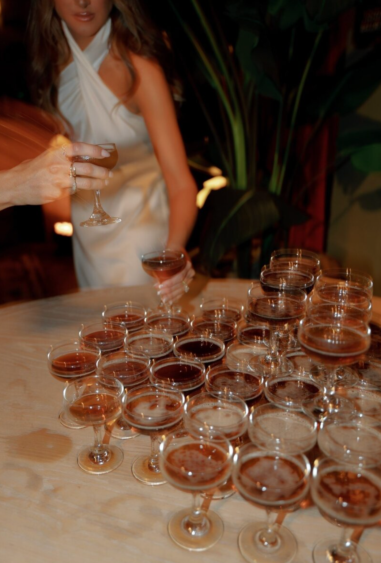 Multiple champagne glasses arranged in rows on a white tablecloth at an elegant event.