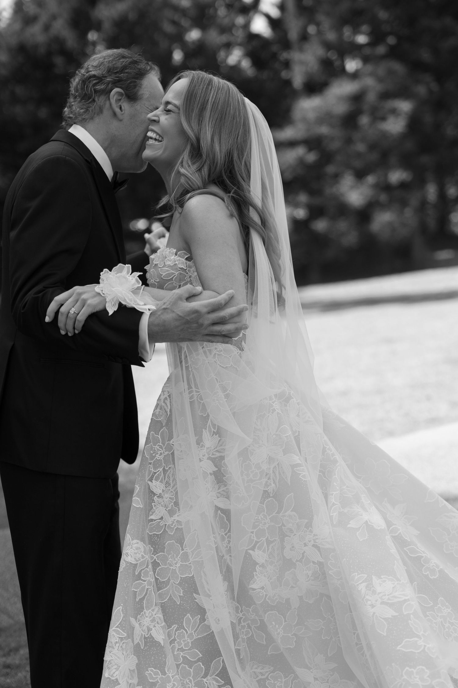A romantic black and white wedding photo of a couple sharing a joyful moment in their formal attire.