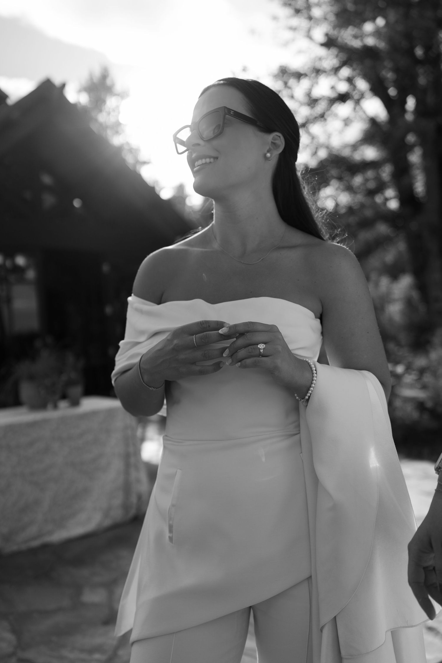 Artistic black and white photo of two people embracing outdoors in flowing white fabric.