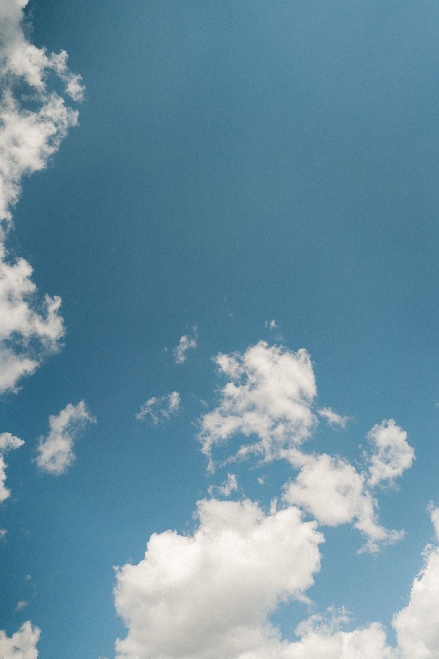 Bright blue summer sky with scattered white puffy clouds.