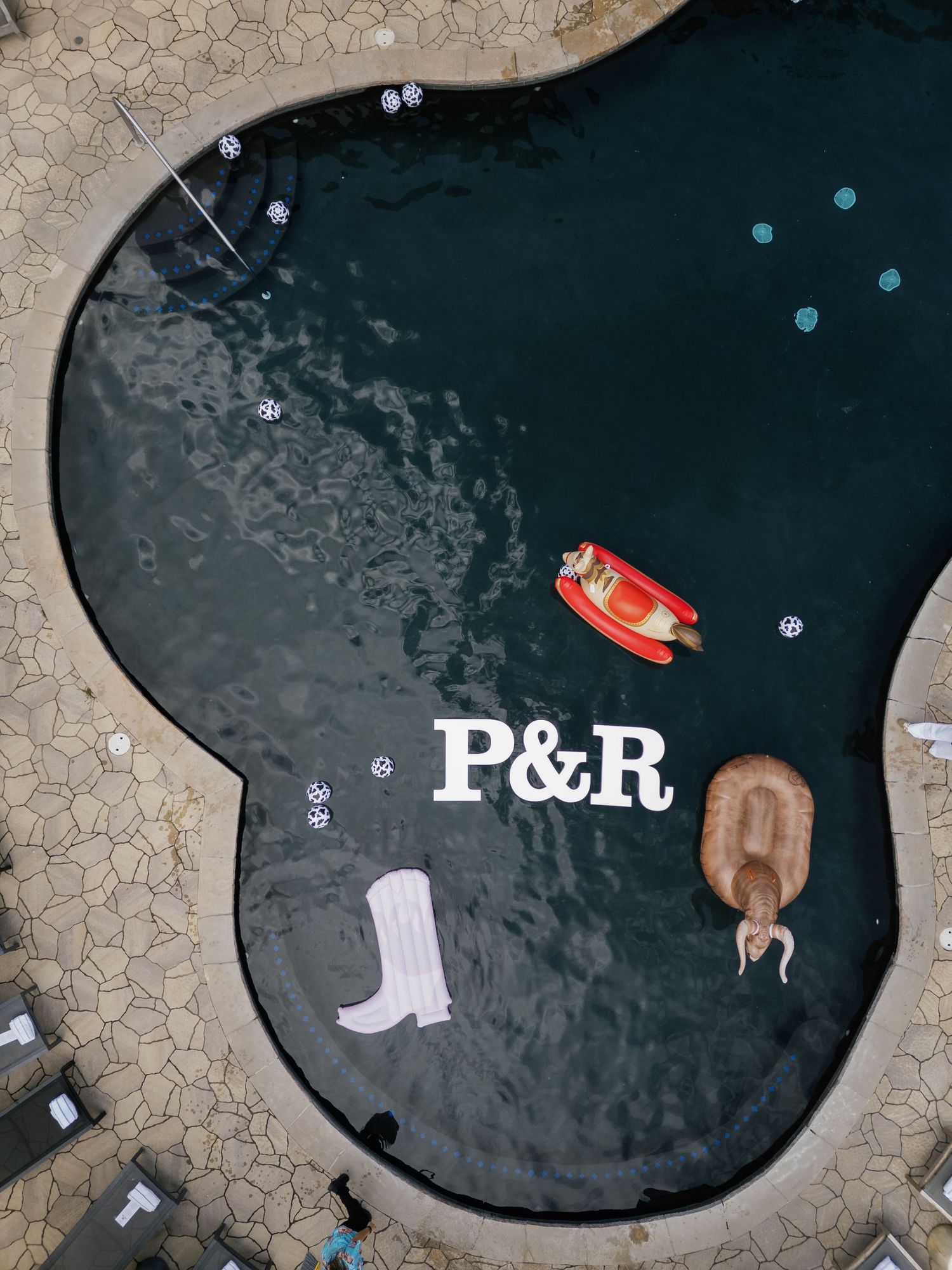 Artistic overhead view of a dark pond surface with scattered wedding items and initials P&R.