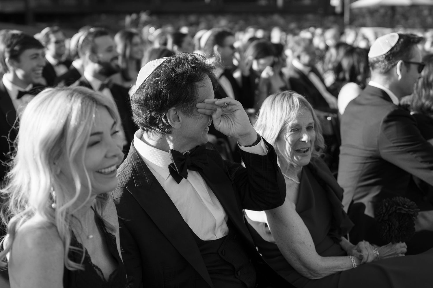 Black and white candid shots of wedding guests laughing and celebrating on the dance floor.