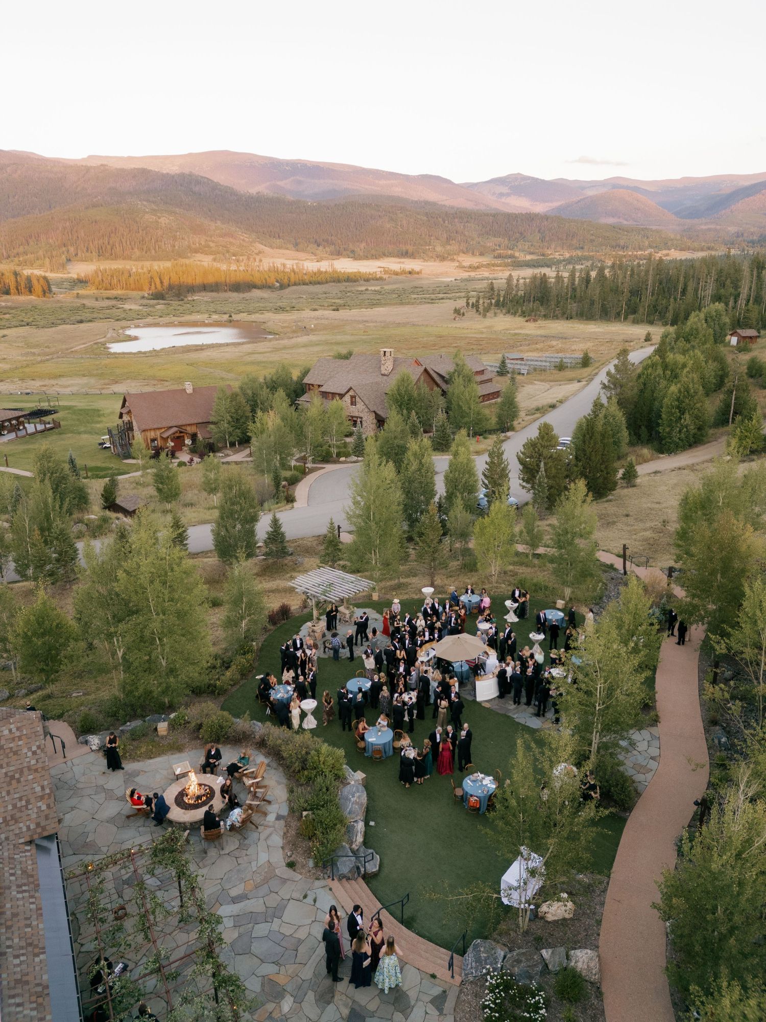 Aerial view of an outdoor mountain wedding venue with guests gathered on a terrace.