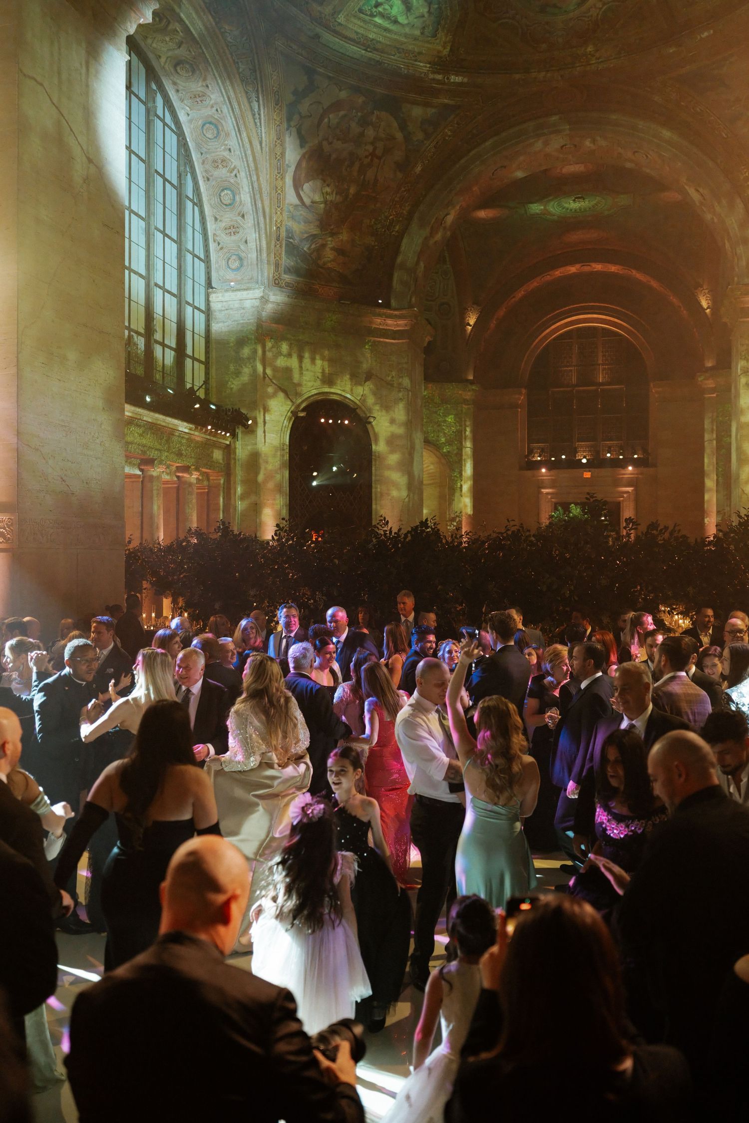 A large, crowded ballroom with people dancing and dressed in formal attire.