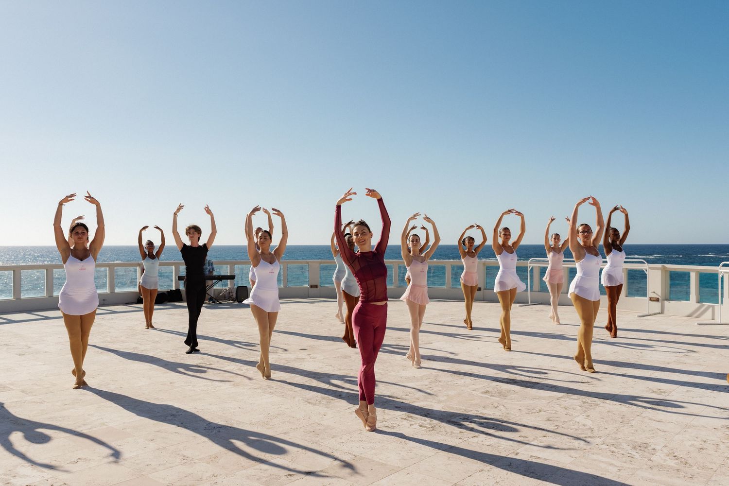 A group of people performing synchronized dance moves on a beach.