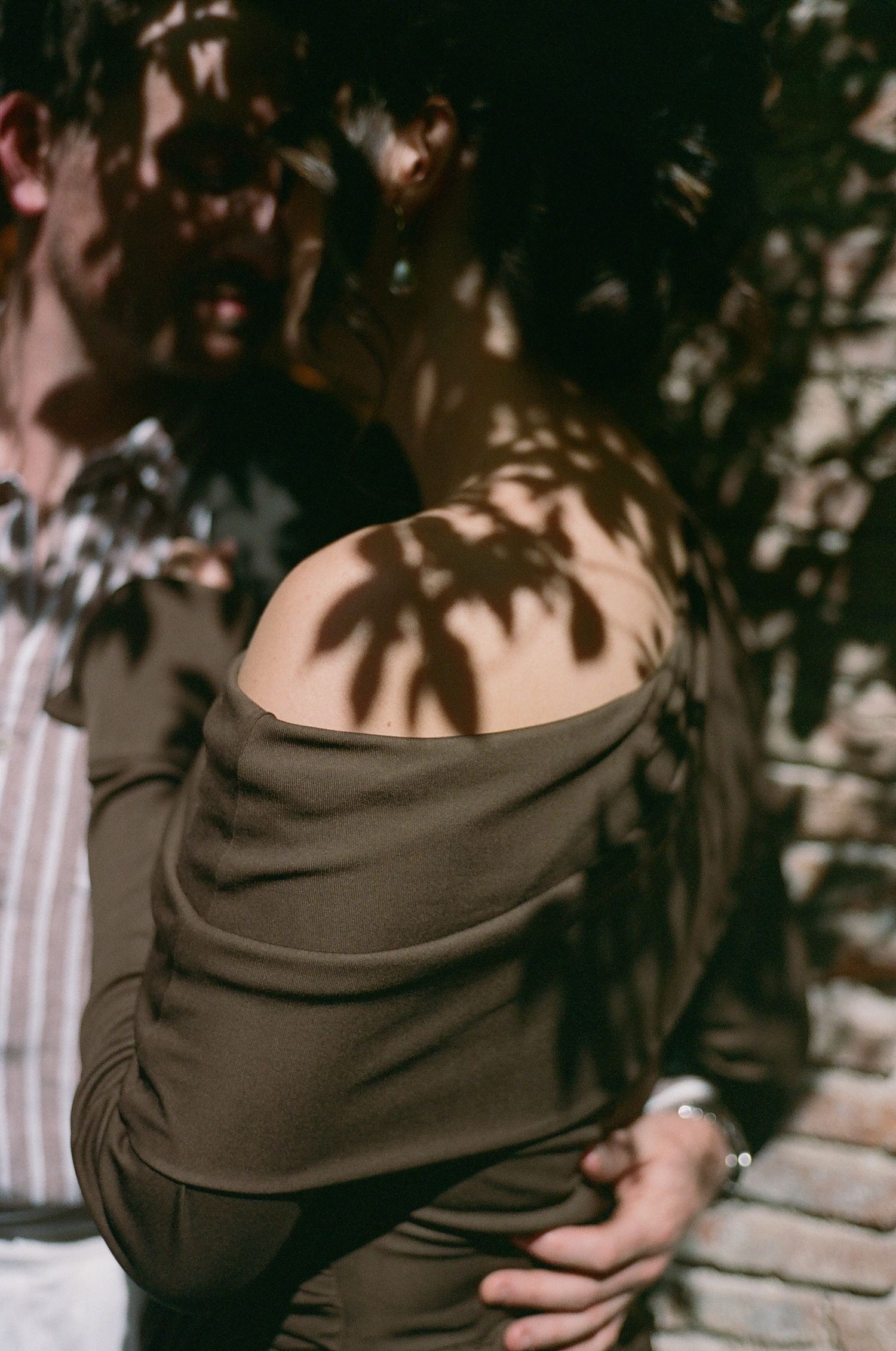 Artistic shot of dappled sunlight creating palm tree shadows on a person's bare shoulder.