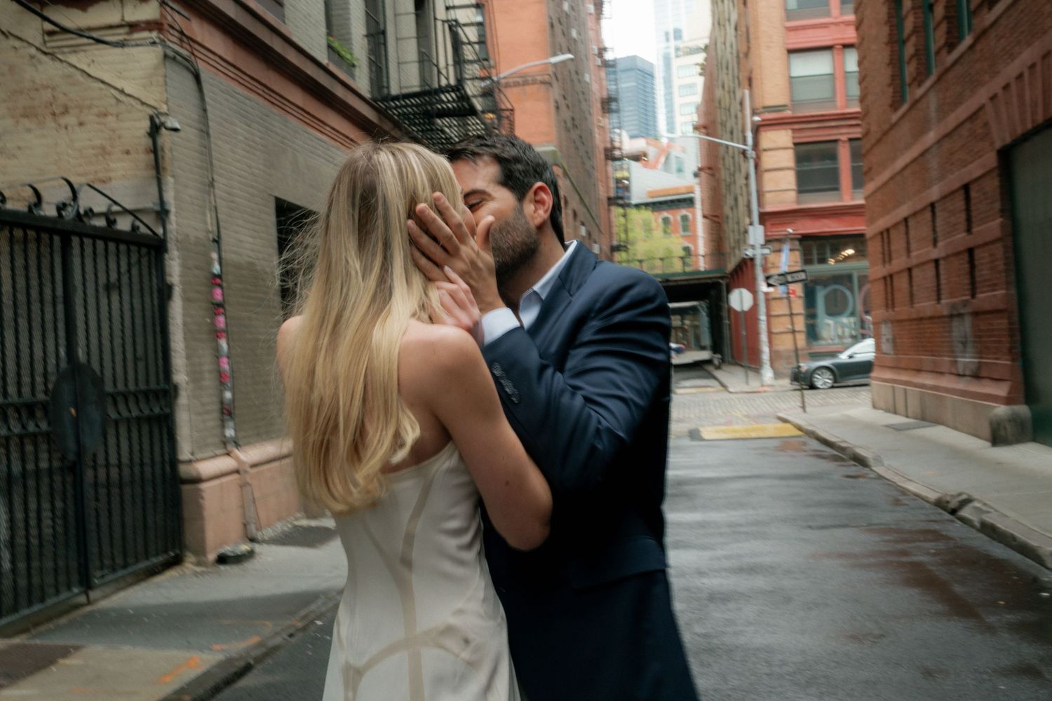 A couple dances and spins together on an urban street with brick buildings.