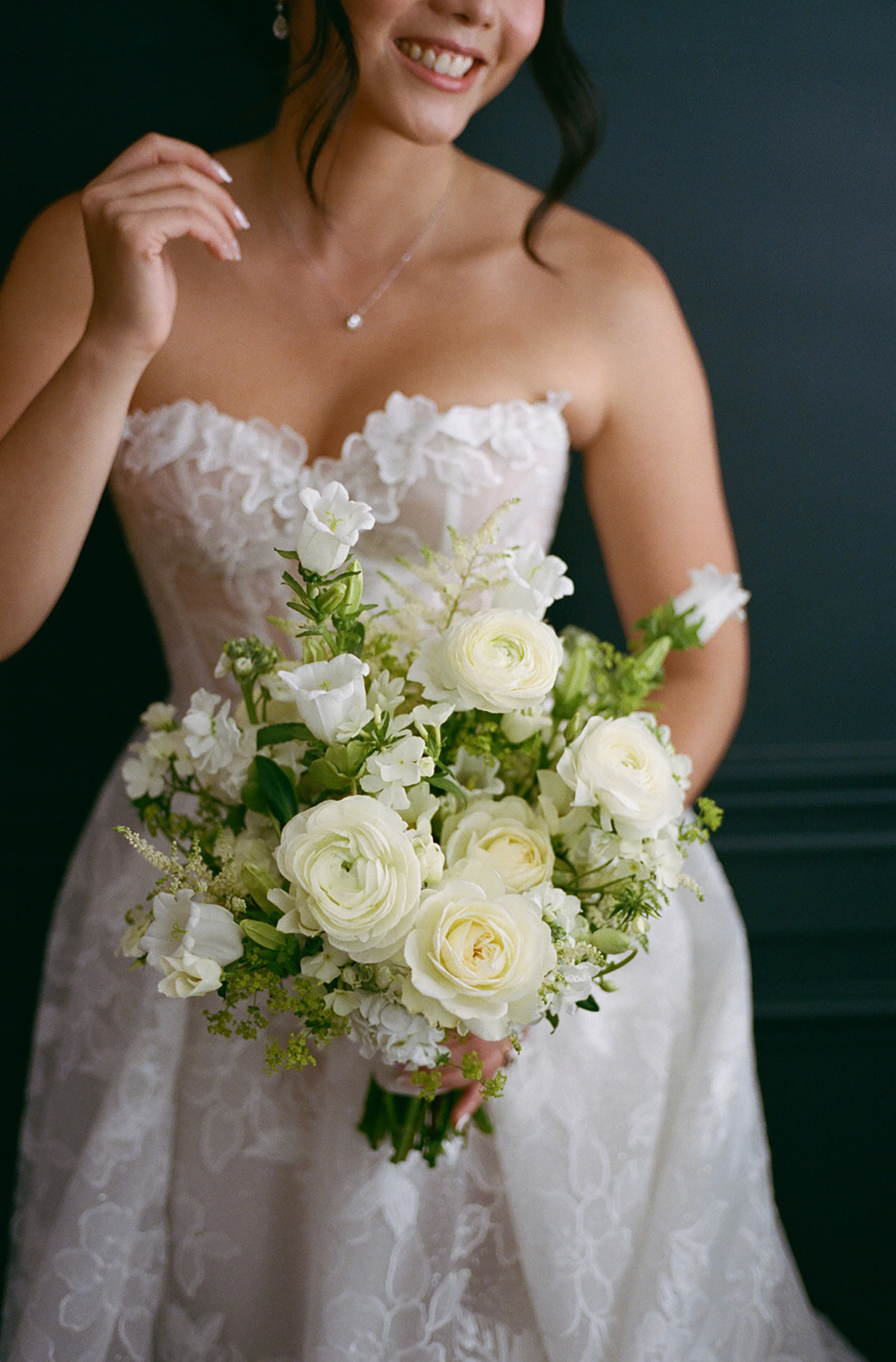 Elegant white bridal bouquet with roses and delicate flowers against a dark background.