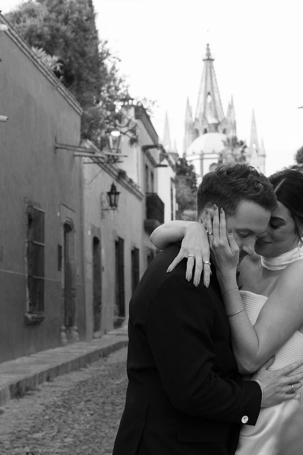 Romantic black and white photo on a cobblestone street with historic church spires.