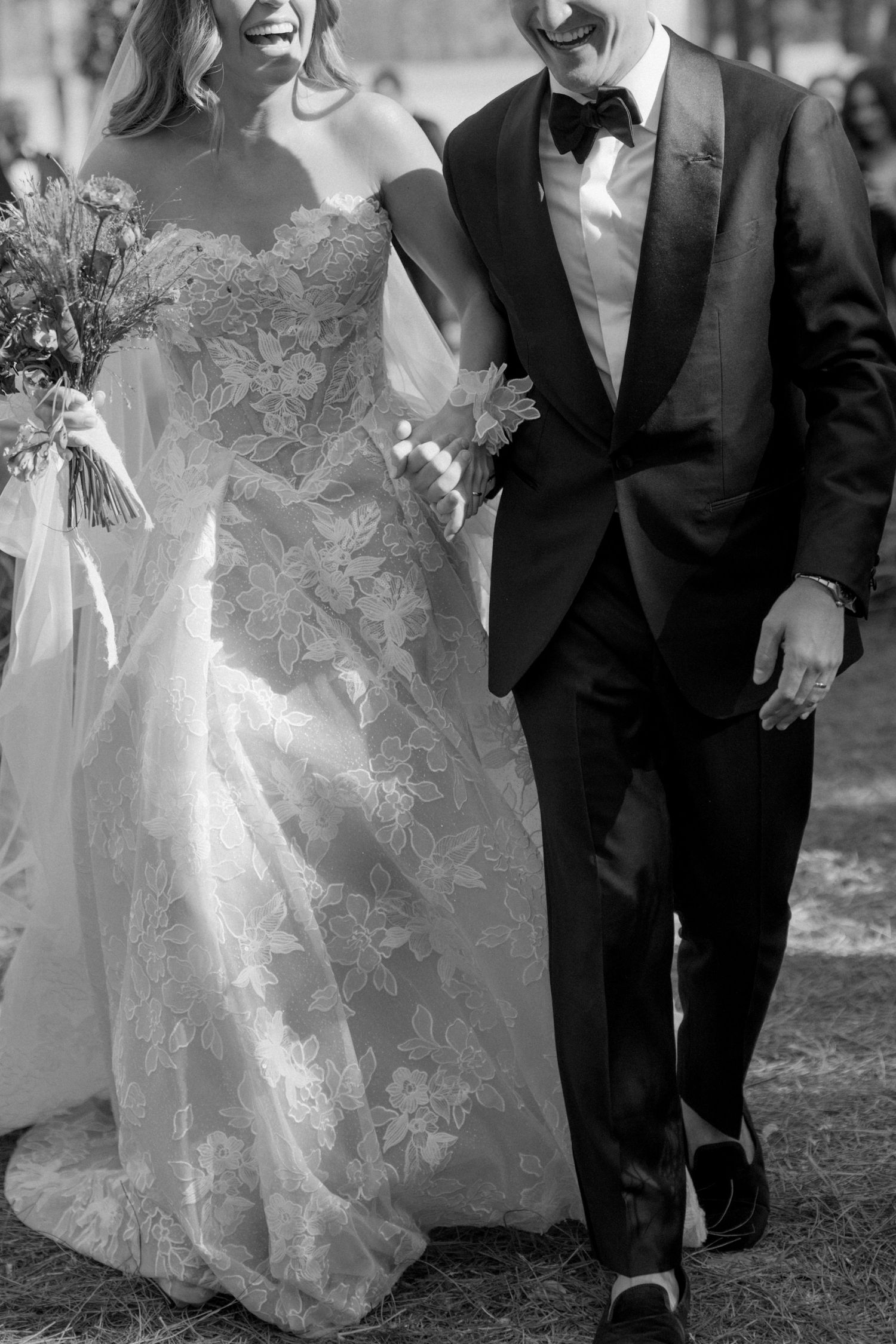 Black and white wedding photo showing elegant lace dress details and formal attire.