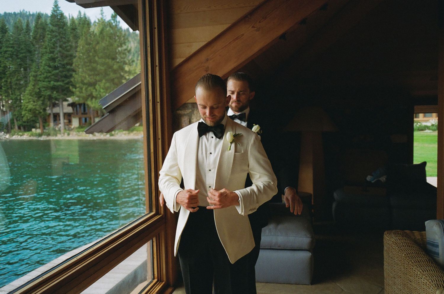 Interior view of a lakeside venue with large windows showcasing the water and forest beyond.