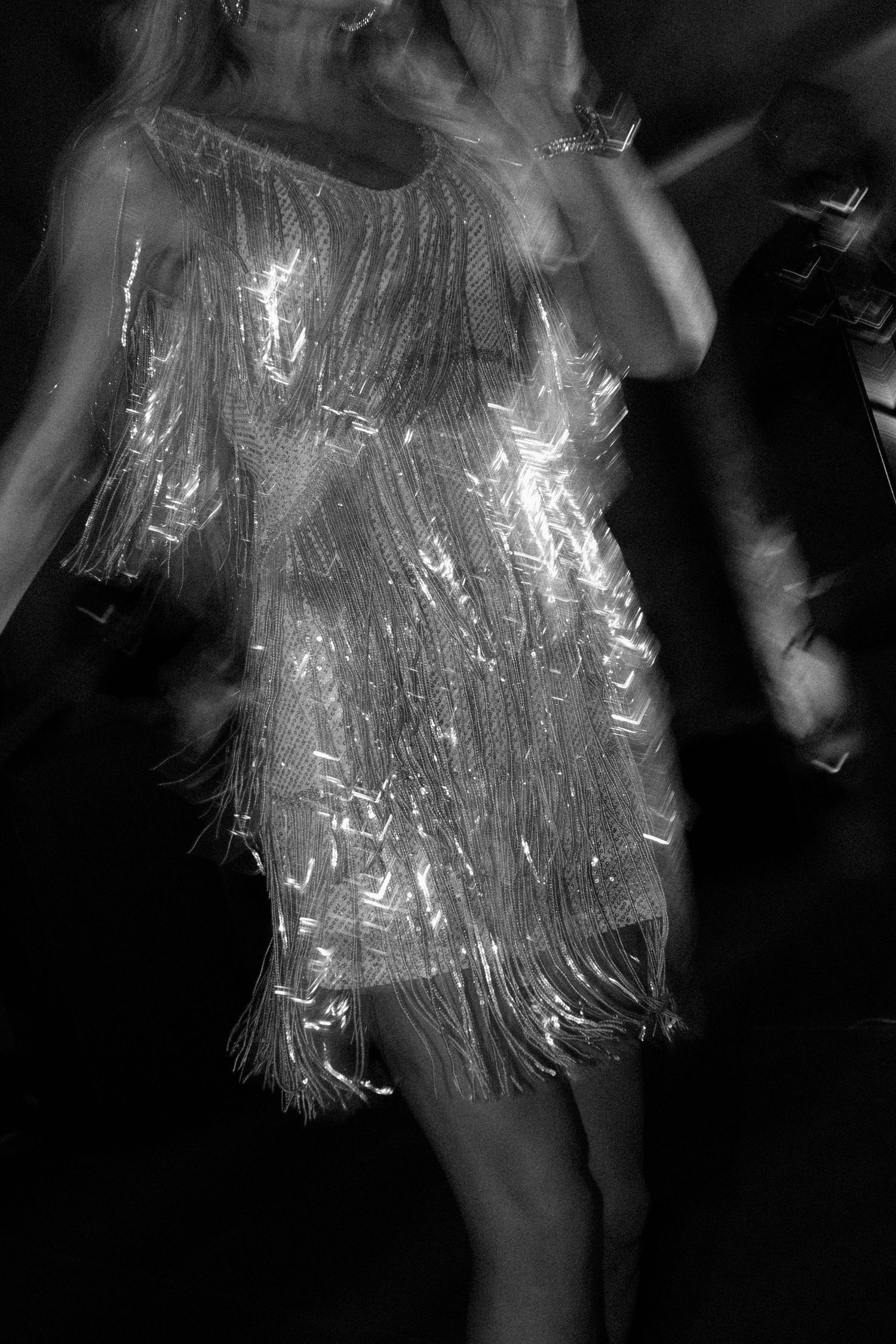 Close-up shots of a shimmering silver fringe dress in motion against a dark background.
