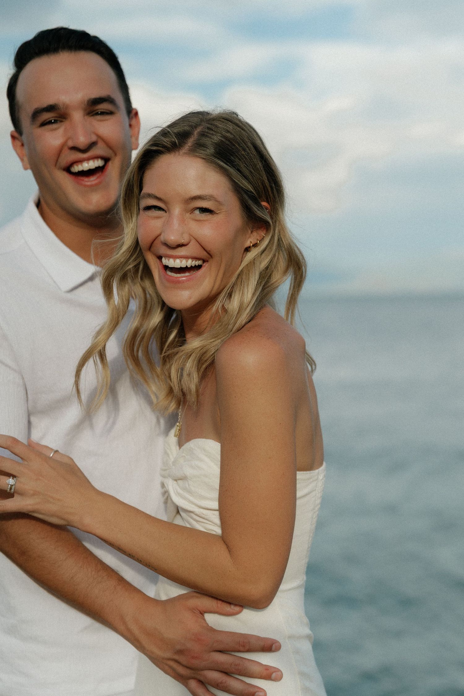 Happy couple sharing a joyful moment together outdoors against a waterfront backdrop.