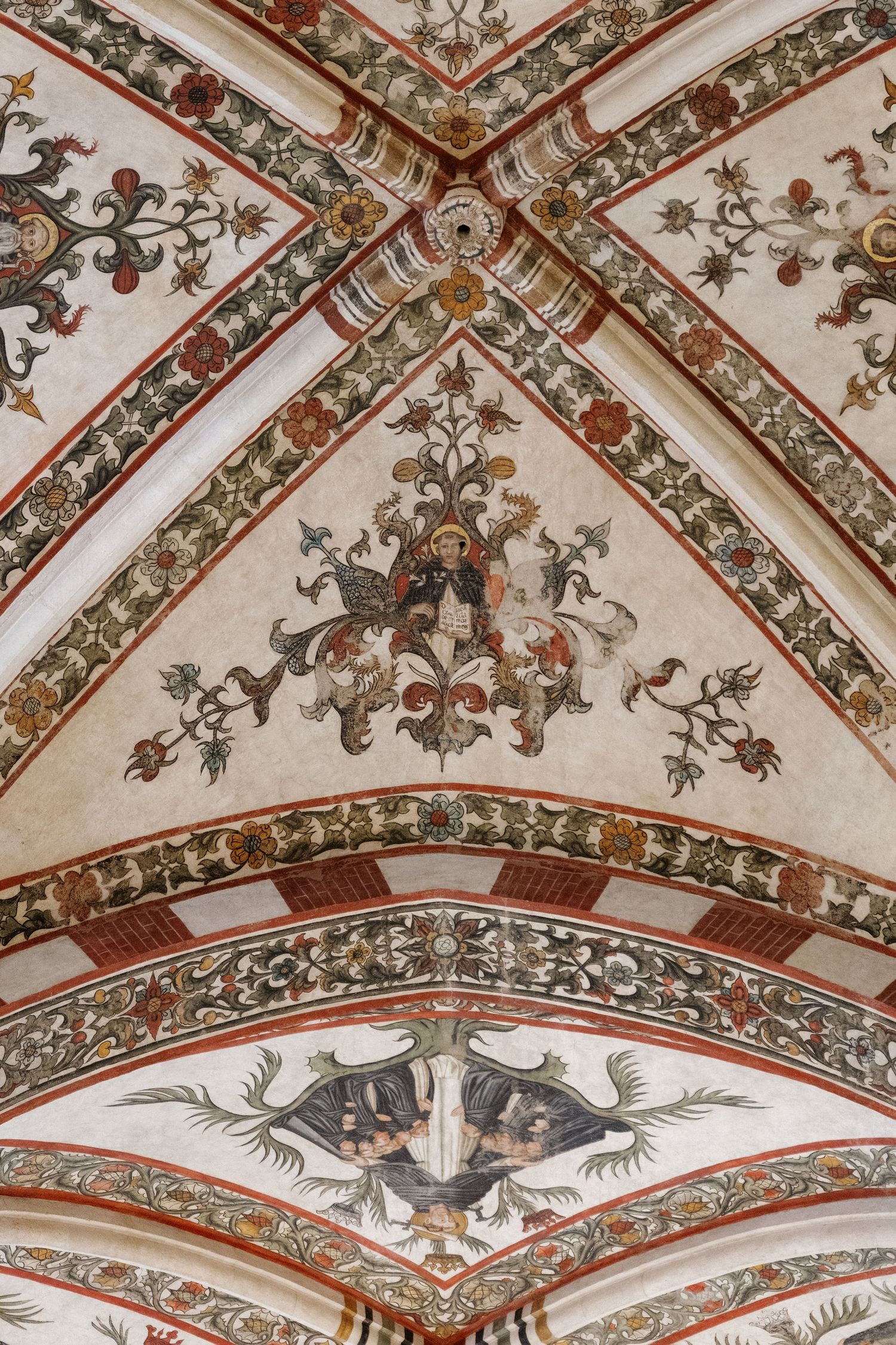 Ornate medieval ceiling fresco with colorful floral and heraldic decorations in Gothic architectural style.