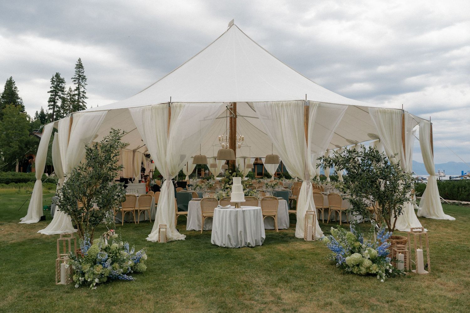 Elegant white wedding tents decorated with greenery and floral arrangements set up outdoors for a special event.