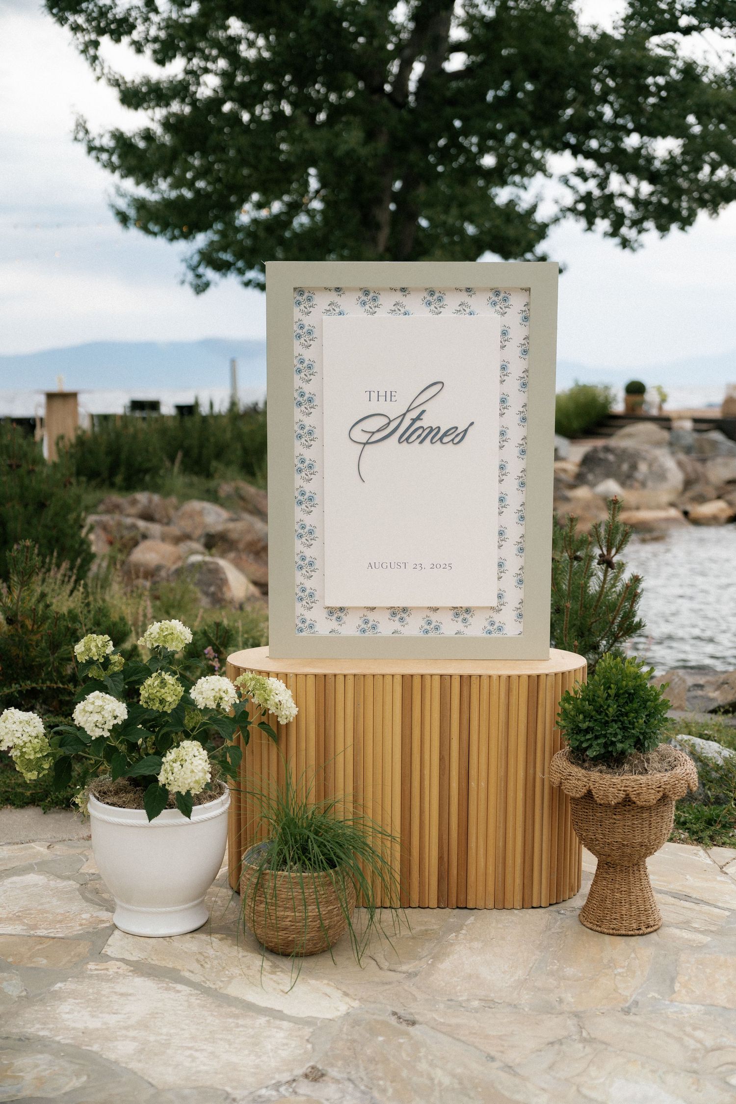 Wedding reception decor featuring wooden elements and white floral arrangements by the waterfront.