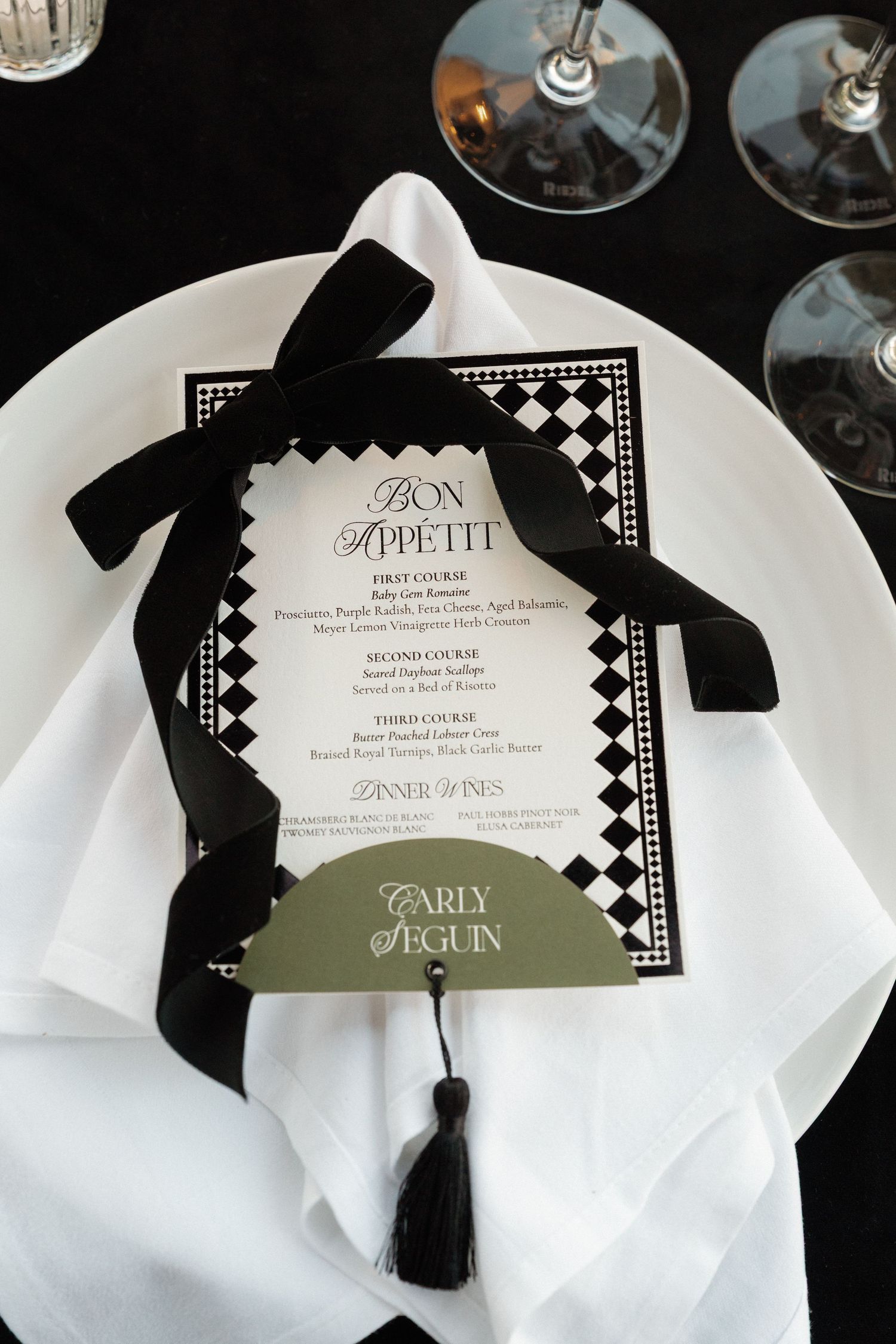 Elegant black and white wedding menu cards with decorative borders on white place settings.