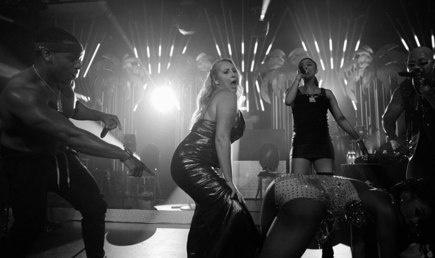 Black and white photo of energetic dancing at a nightclub with dramatic lighting effects.
