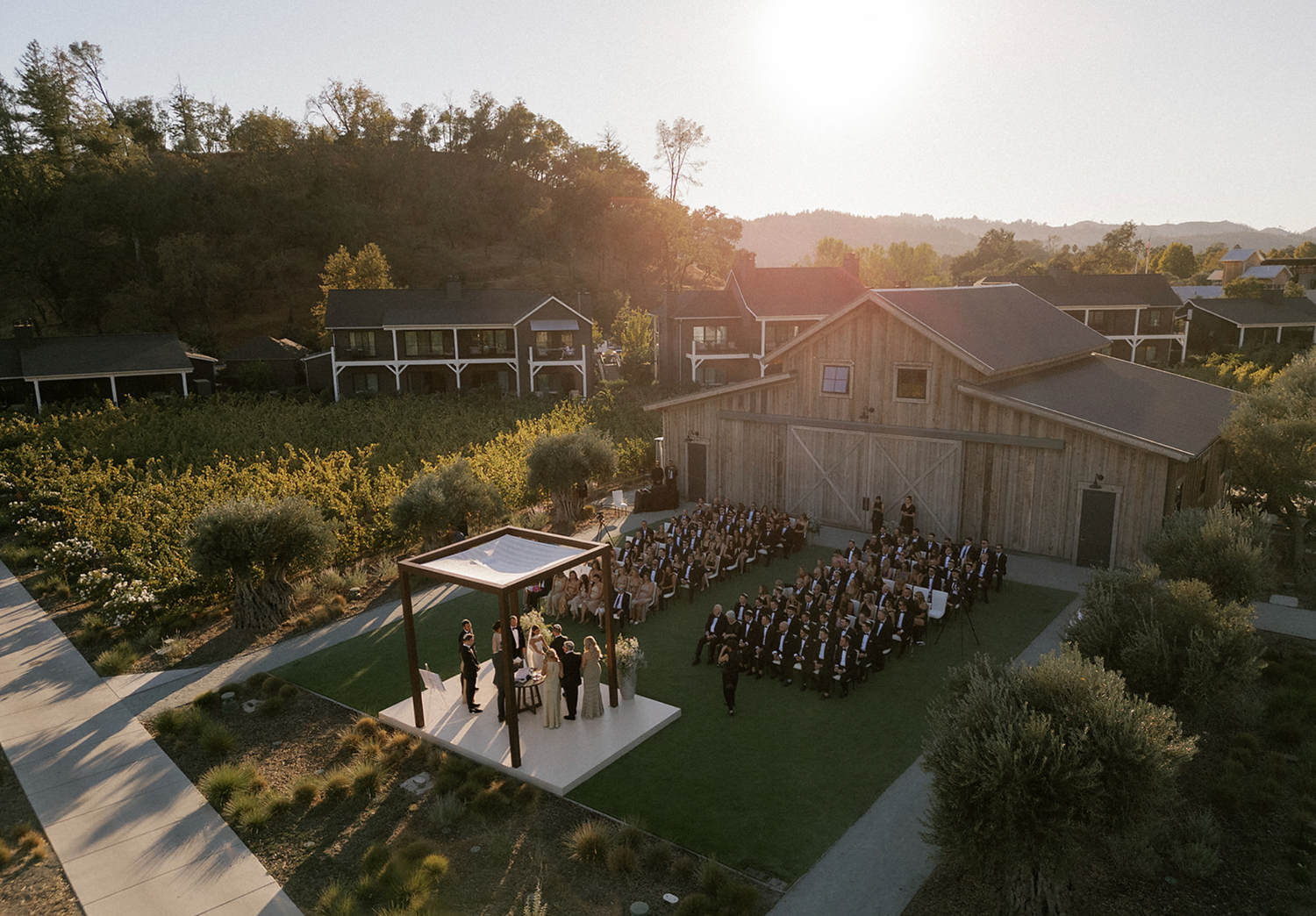 Aerial view of wedding venue at sunset showing outdoor ceremony and reception spaces.