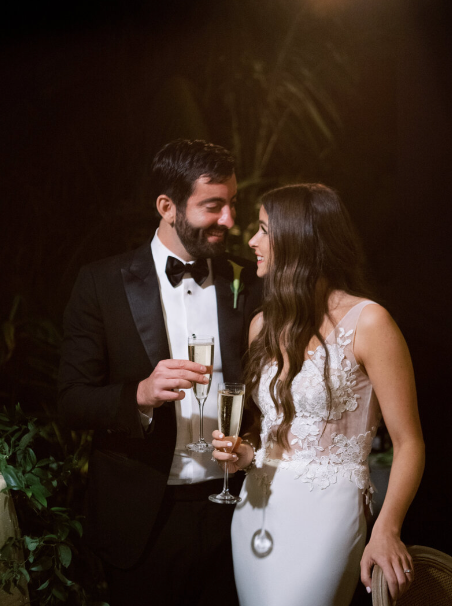 Romantic moment between newlyweds sharing champagne at an evening celebration.