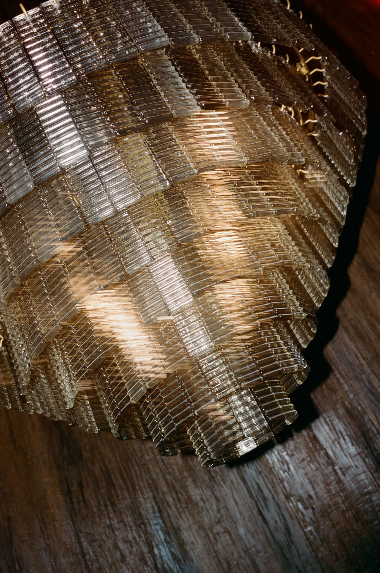 Crystal chandelier with geometric patterns casting warm reflections on wooden floor.