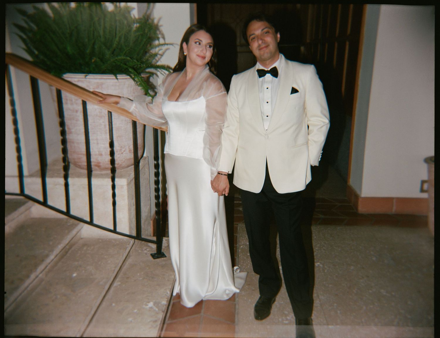 A formal couple poses on stairs during an elegant evening event.