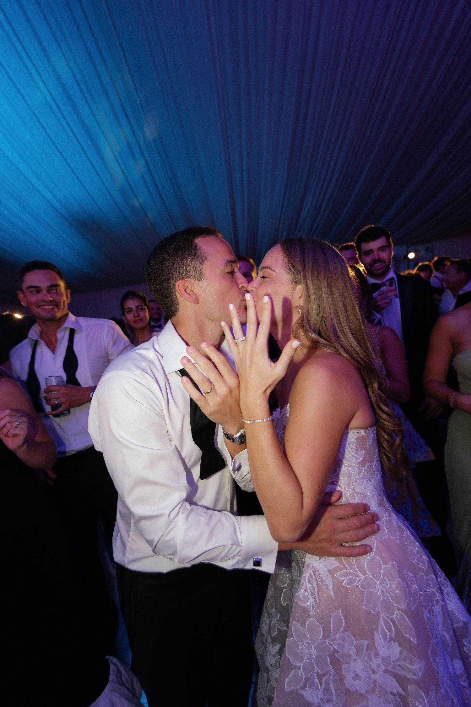 Romantic moment on the dance floor under blue lighting at a wedding reception.