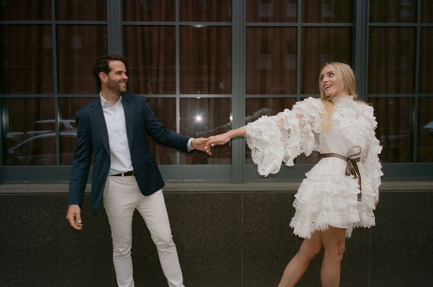 A couple dancing and twirling in elegant attire on a city street.