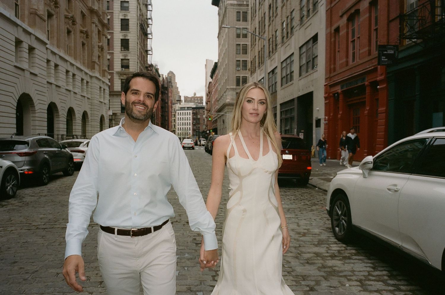 Two people walking together on a charming cobblestone street in an urban setting.