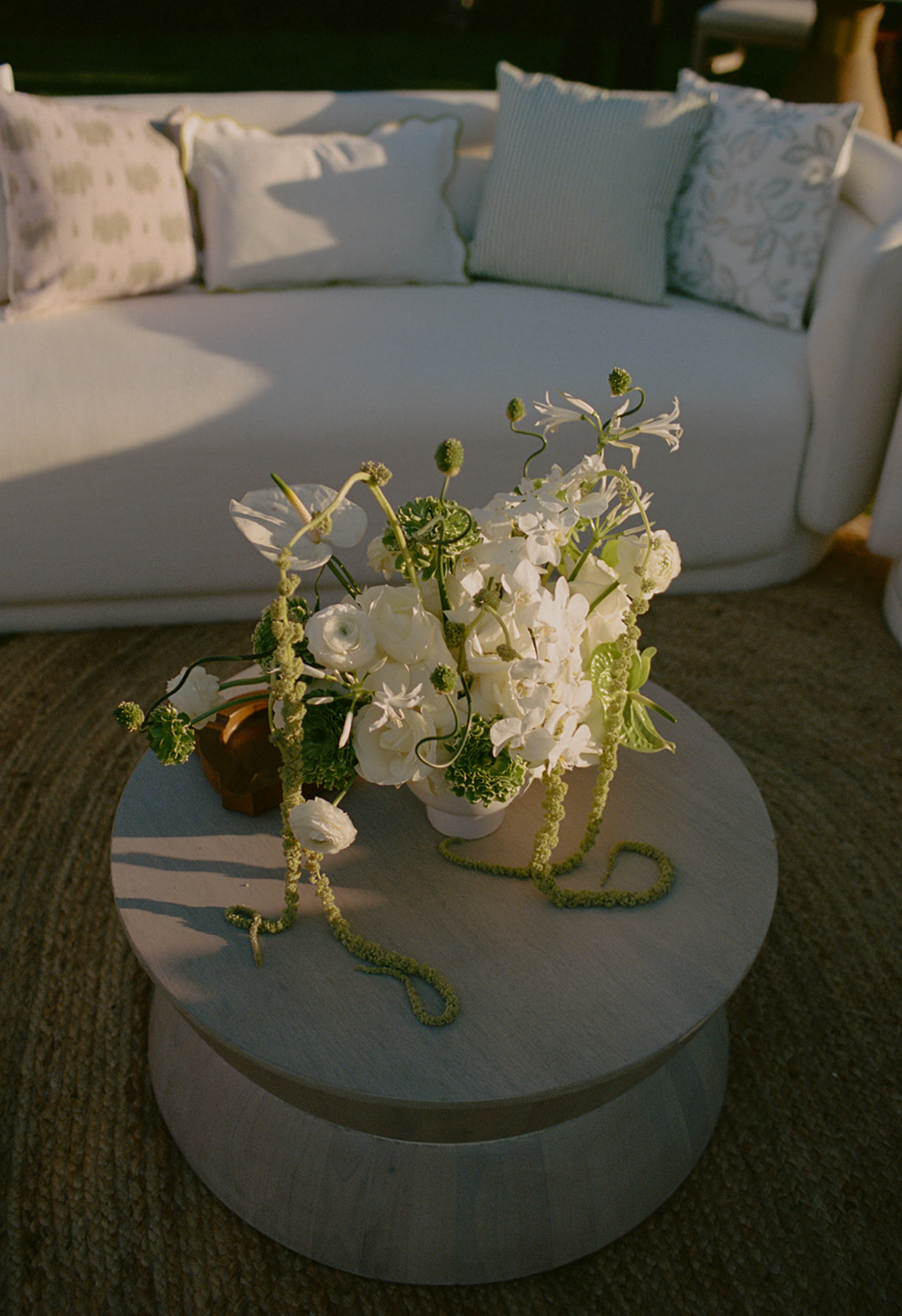 White floral arrangement with delicate blooms displayed on a round gray coffee table.