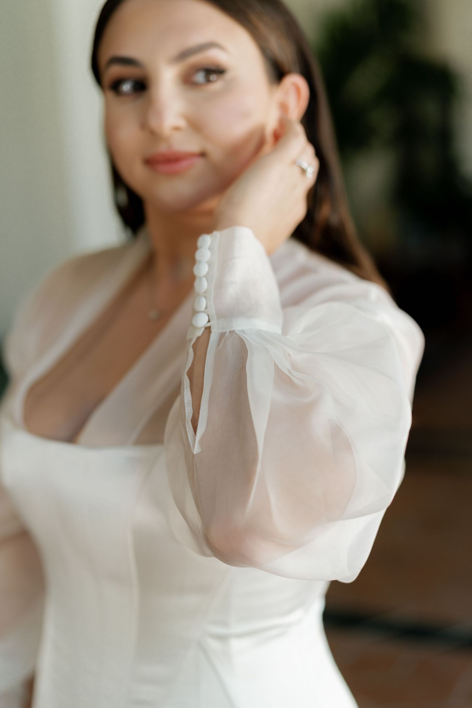 A close-up shot of a wedding dress featuring delicate sheer puff sleeves and a structured bodice.