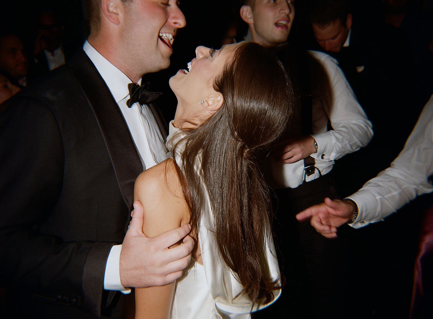 Couples dancing intimately at dimly lit wedding reception.