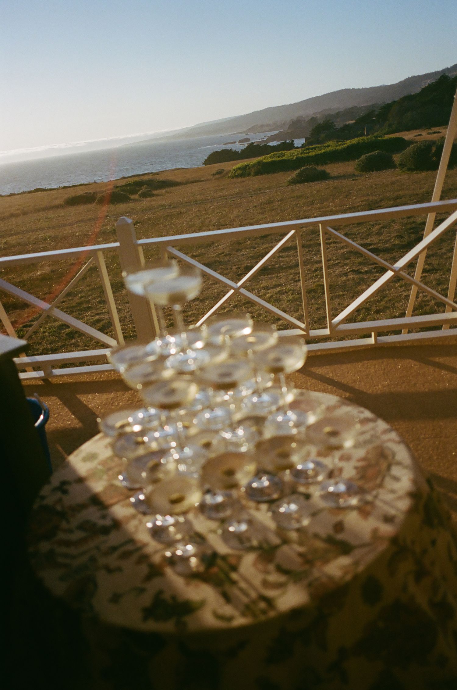 Crystal chandeliers hanging over an outdoor terrace with ocean views in the background.