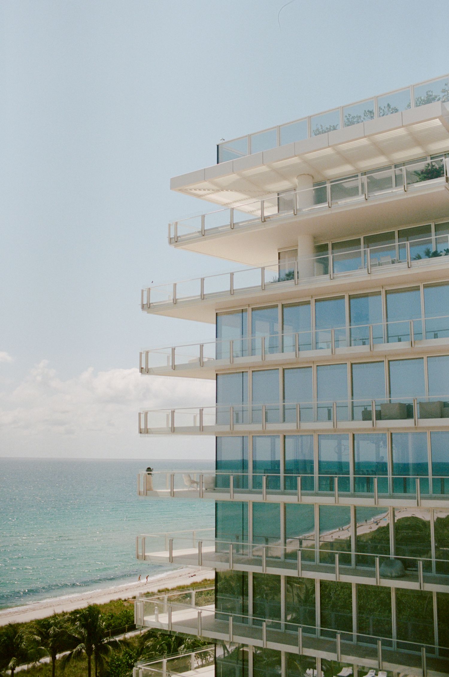 Modern oceanfront hotel building with glass balconies overlooking the beach.