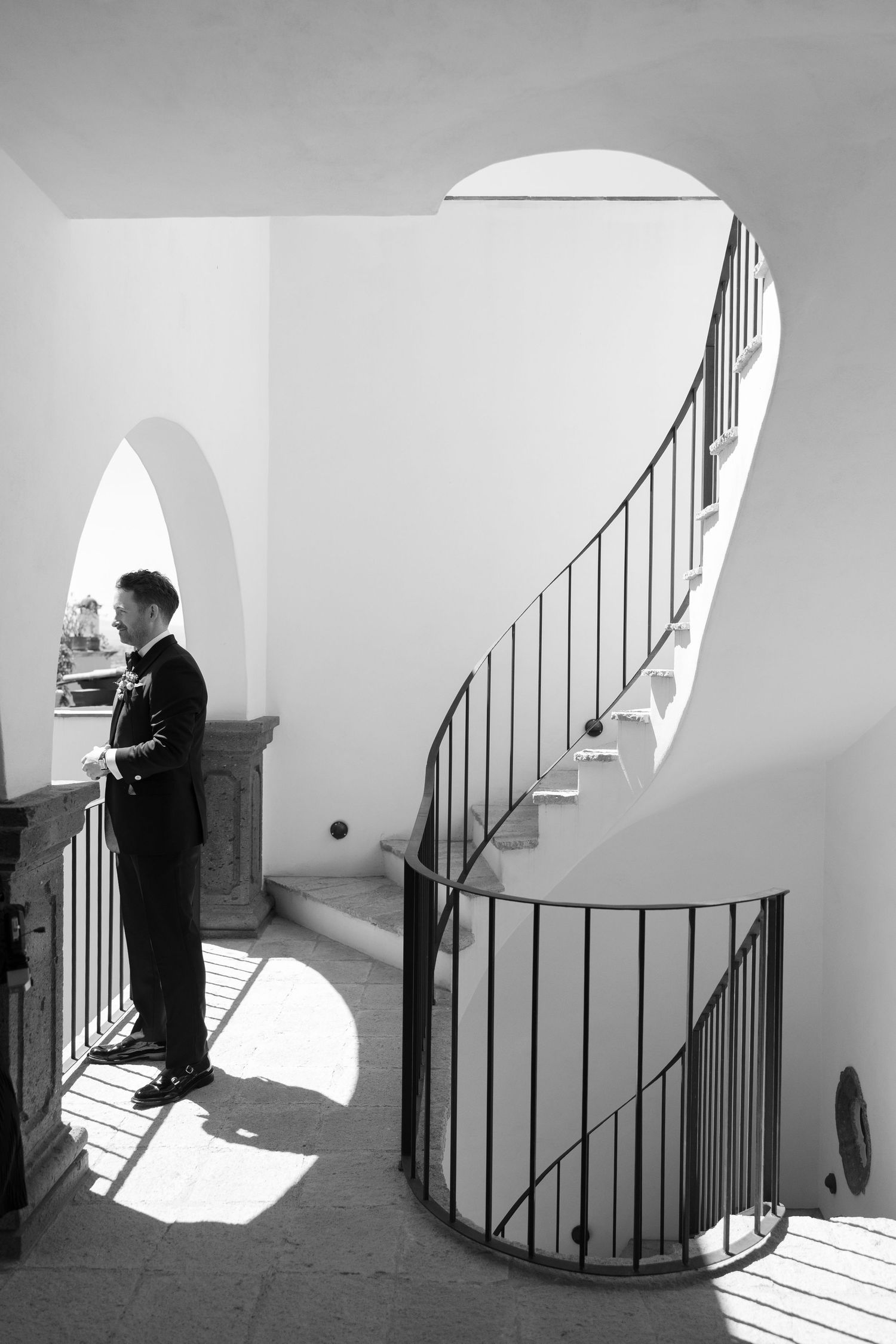 Black and white architectural series showing dramatic light and shadows on a curved staircase.