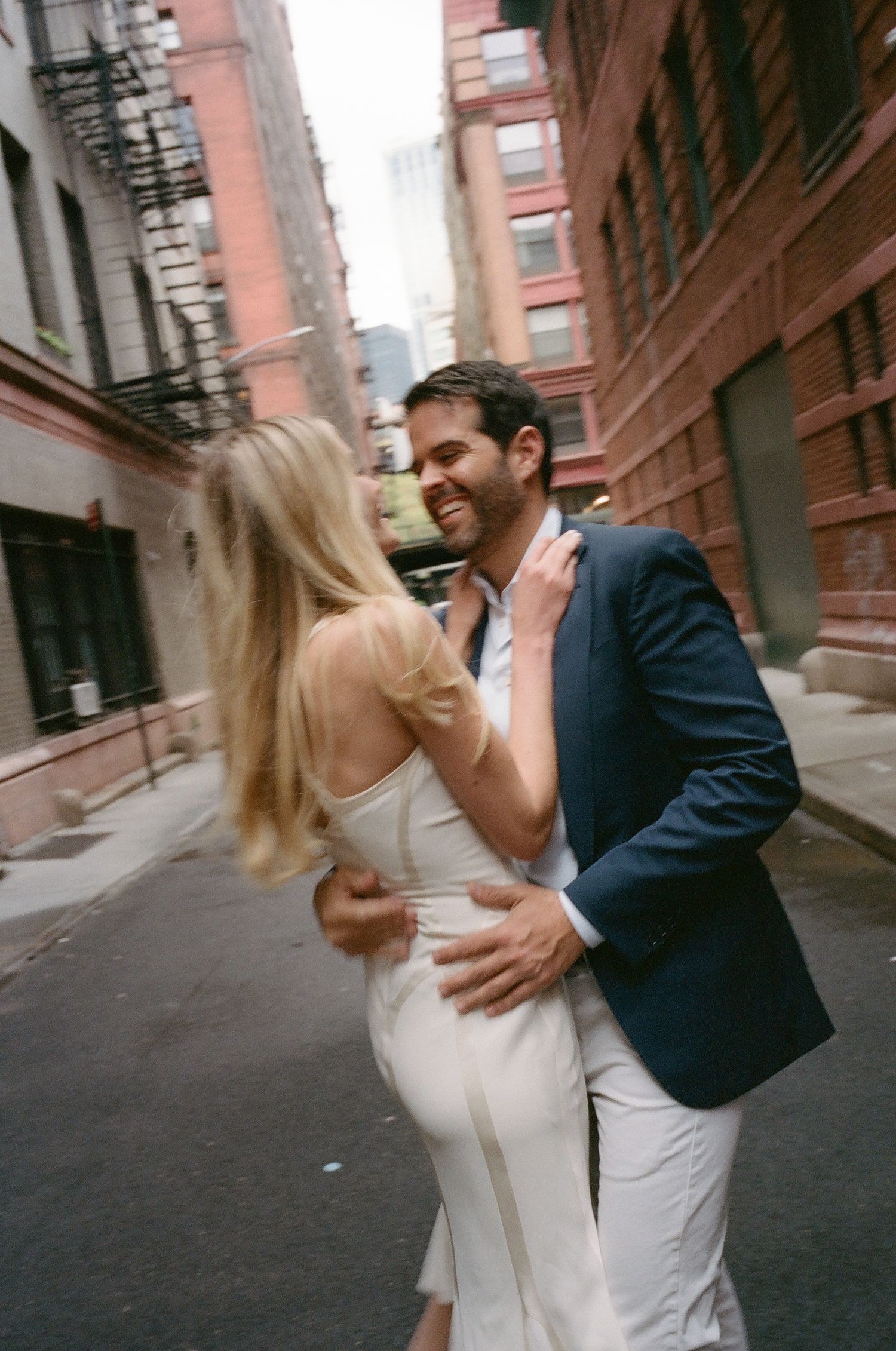 Couple dancing in an urban alley surrounded by brick buildings.