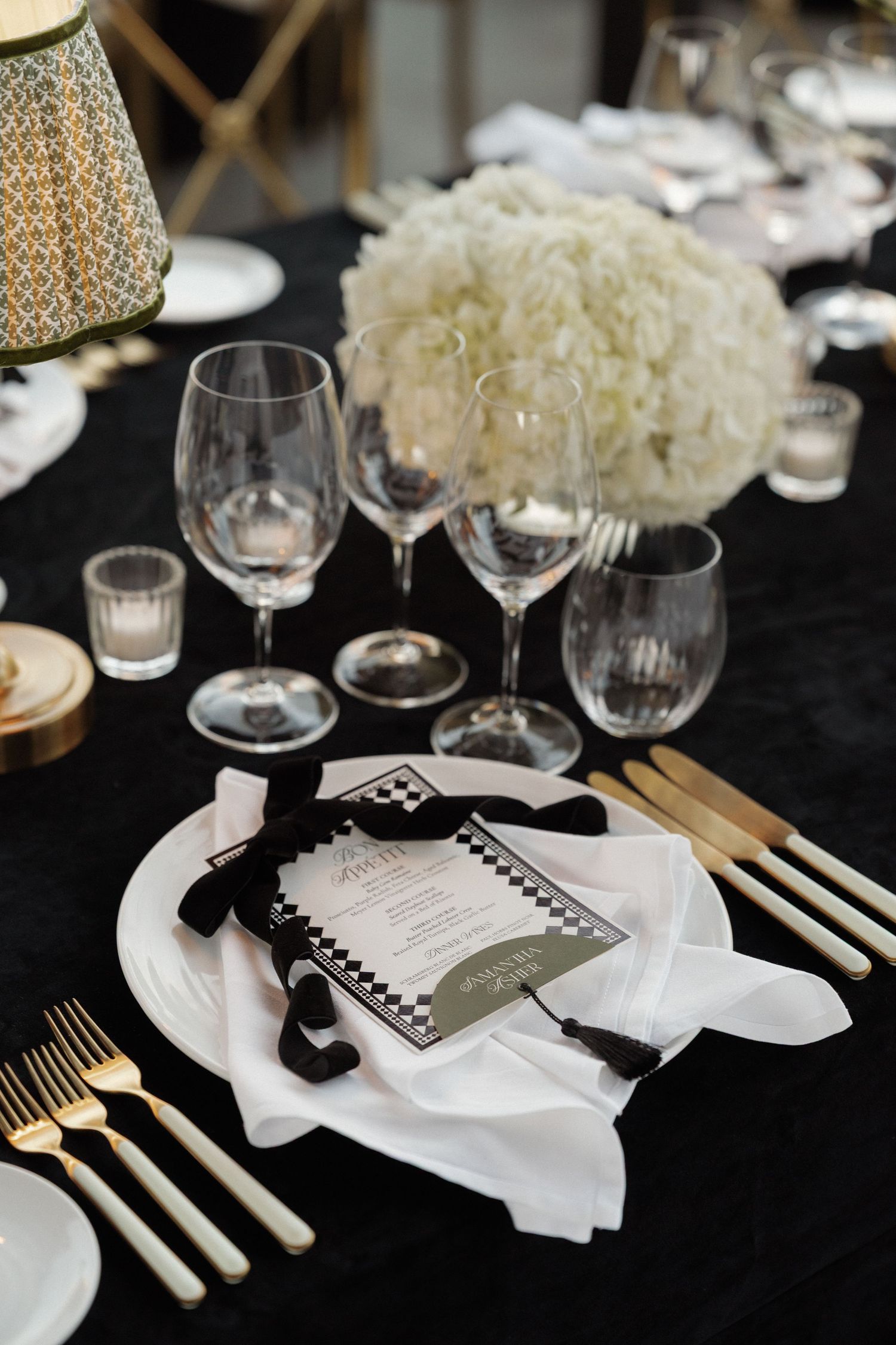 Formal table setting with white plates, gold cutlery, and black accents for wedding reception.