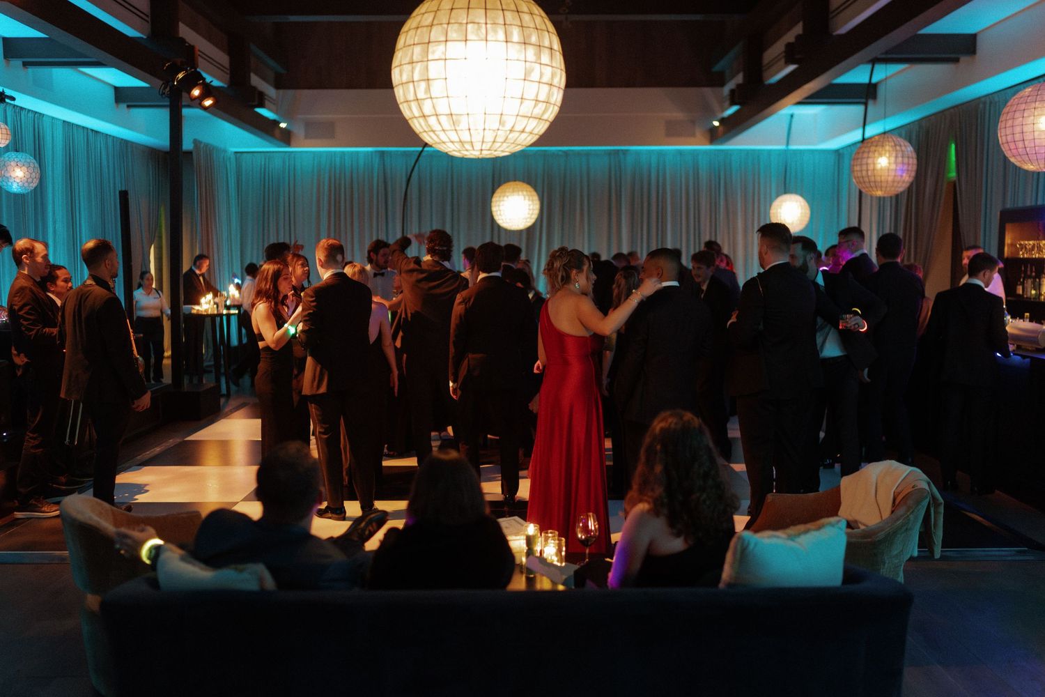 Modern event space with spherical pendant lights and turquoise accent lighting along the walls.