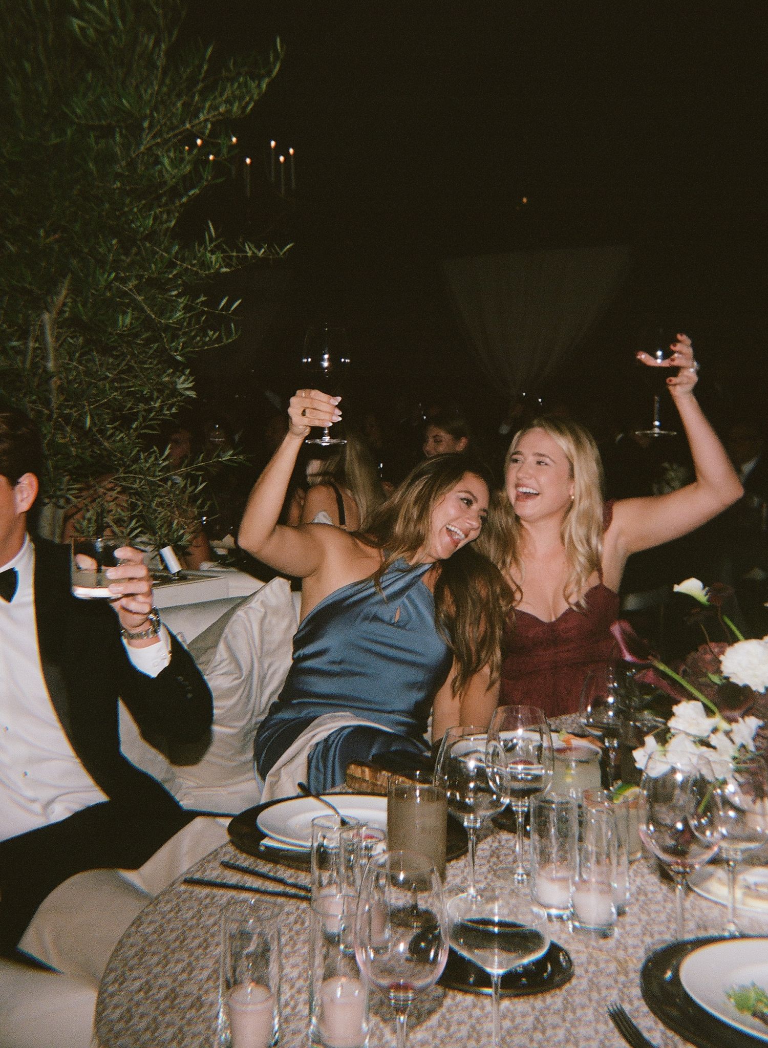 Candid reception dinner scene with guests celebrating at a decorated table.