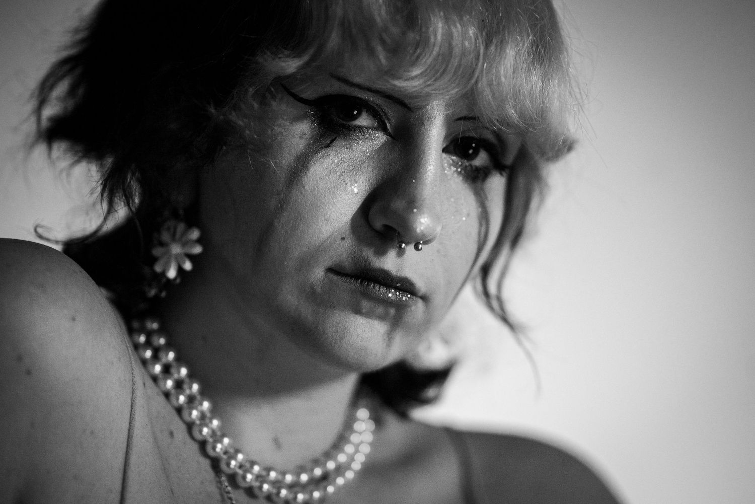 Dramatic black and white portrait series showing vintage-style glamour shots with pearl necklace and moody lighting.