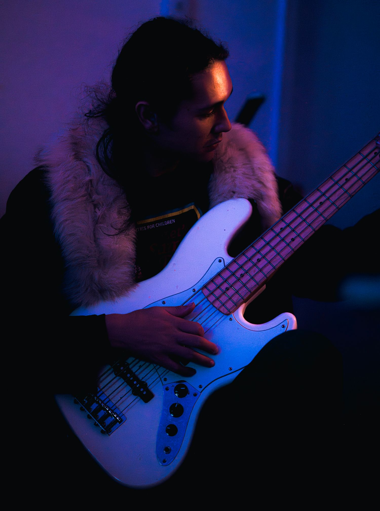 Bass guitarist playing in moody blue lighting during a performance.