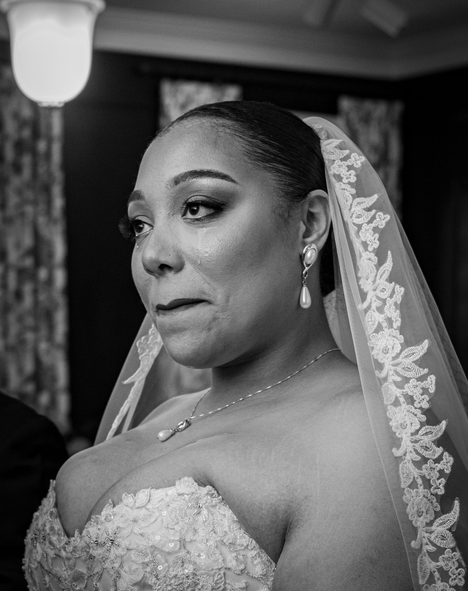 Bride wearing lace veil in classic black and white portrait series.